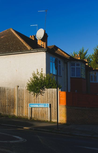 A two-storey residential house with a sloped tiled roof, situated on Candover Road, Crayford, with a white exterior wall and blue window frames on the upper floor. On the roof, there is a satellite di