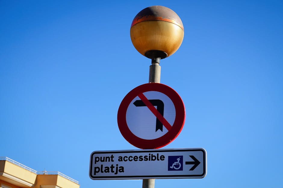 A close-up view of a designated accessible parking space on an asphalt surface, featuring a yellow painted wheelchair symbol in the center, surrounded by yellow diagonal lines indicating a no-parking zone. The surface shows slight wear and tire marks, with the parking area situated near a building entrance, which is partially visible in the background. The space is empty, ready for vehicle parking associated with house removals or relocation services. This parking area is part of a commercial or residential location, with the space allocated for ease of access during furniture transport, packing, and moving activities handled by Man and Van Crayford, a company specialising in removals and home relocation services.